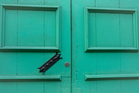 Puerta antigua de madera verde con cerradura y herraje decorativo