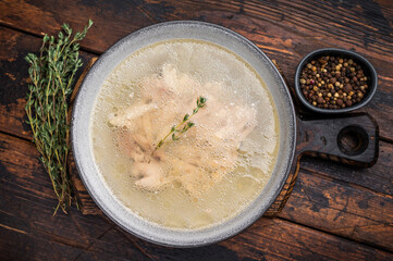 Bowl of clear chicken broth with meat. wooden background. top view