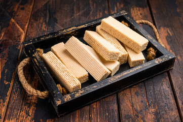 Wafer stick biscuits with vanilla cream in wooden tray. wooden background. top view