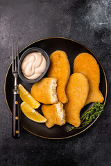Crispy fried cod Fish sticks on plate. black background. top view