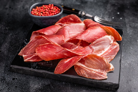 Sliced prsut prshut, Balkan cured pork meat ham. black background. top view