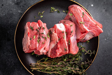 Raw mutton cut rib chops, fresh lamb meat with herbs for grilling. black background. top view