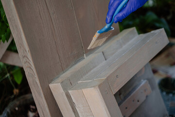 The process of gray painting a wooden step. A woman paints a wooden product. 