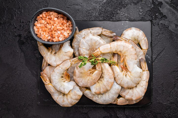 Raw headless white shrimps prawns on a marble board. Top view. Black background