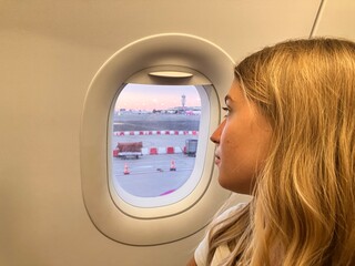 Ragazza bionda guarda attraverso obl&ograve; dell&rsquo;aereo 