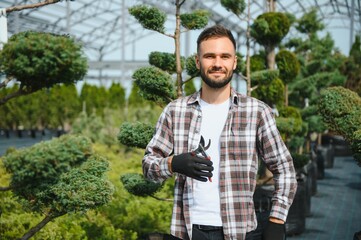 Portrait of a young handsome gardener. Shop of tree sprouts.