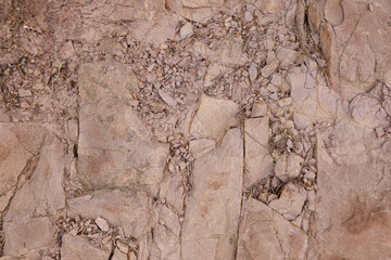 Brown rock texture with a rough, uneven surface and small stones. Ideal for use in architecture, design, construction, ecology, and education