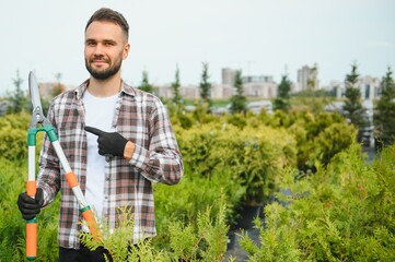 A young gardener cuts a tree with scissors. Gardening and tree shop concept