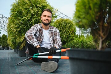 A young gardener cuts a tree with scissors. Gardening and tree shop concept