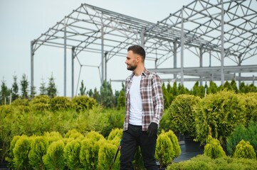 A young gardener cuts a tree with scissors. Gardening and tree shop concept