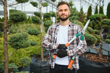 Portrait of a young handsome gardener. Shop of tree sprouts.