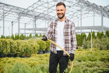 Garden worker watering grass and bushes