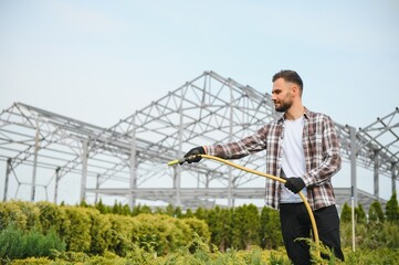 A young gardener cuts a tree with scissors. Gardening and tree shop concept