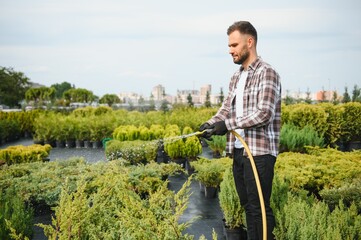 Garden worker watering grass and bushes