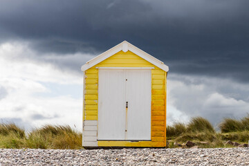 gelbe Strandh&uuml;tte mit dunklen Gewitterwolken im Hintergund