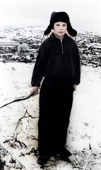 Vintage portrait of a boy in a fur hat with earflaps in winter, holding a stick in his hand. Retro...