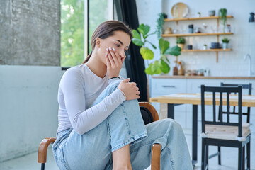 Fototapeta premium Sad upset teenager girl sitting at home in living room