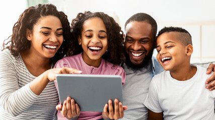 Free Time Together. Portrait of positive black parents and children digital tablet together at home, watching family photos or funny comedy video online, people laughing sitting on sofa in living room