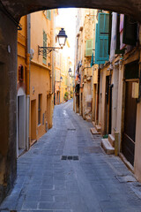 Narrow street in the historic center of the southern French city of Menton with stone houses and colorful facades