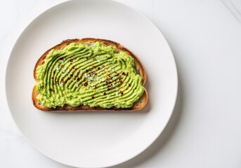 Artfully prepared avocado toast with a decorative wavy spread, seasoned with salt and pepper on a white plate.
