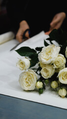 Beautiful white roses in a flower shop. Florist assembles a bouquet to order