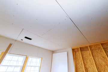 Drywall being installed in residential room, with visible seams natural light coming through...