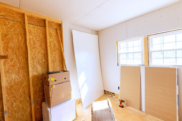Sunlight floods room under renovation, showcasing drywall sheets tools ready for installation during works daytime renovations