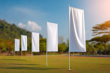 Several rectangular white flags stand on poles in a grassy field under a sunny blue sky, offering ample space for unique customization.