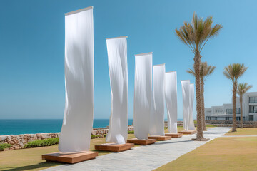 Fototapeta premium Row of white banners by the ocean at a seaside resort creates an airy, artistic atmosphere with palm trees and blue sky.