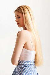 Naklejka premium Model poses elegantly in studio setting showcasing long blonde hair and minimalistic fashion