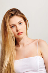 Naklejka premium Young woman with long hair posing confidently against a neutral background in a casual attire during a studio session