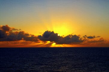 sun behind clouds at sea