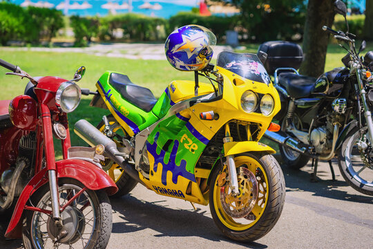 Colorful Yamaha FZR motorcycle in vivid yellow, green, and blue paint with helmet on seat. Concept of sport bike power, freedom on road, motorcycle lifestyle