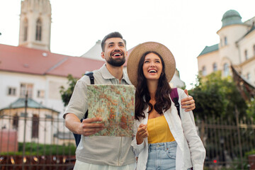 Excited couple walking with map in the city, spending vacation by exploring the streets of old...
