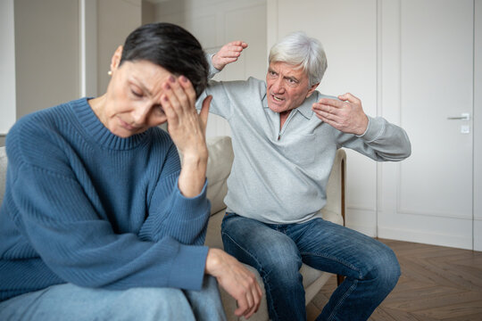 Irritated senior man shout gesturing at distressed sad wife, showing emotional instability. Senior couple family discord, marital breakdown, verbal aggression, mental fatigue, relationship exhaustion