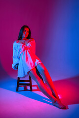 Model posing artistically with colorful lighting effects in a studio setting during a creative photoshoot in the evening