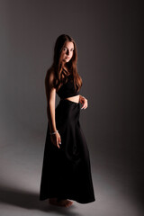 Fototapeta premium Elegant model posing in a black dress against a neutral backdrop during a studio photoshoot