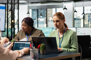 Empowered team of diverse women utilizes laptop in a corporate workspace, demonstrating...
