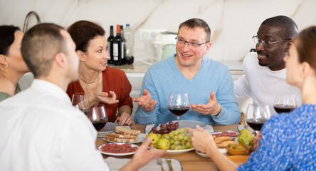 Multiethnic women and men friends talking and drinking wine in the kitchen