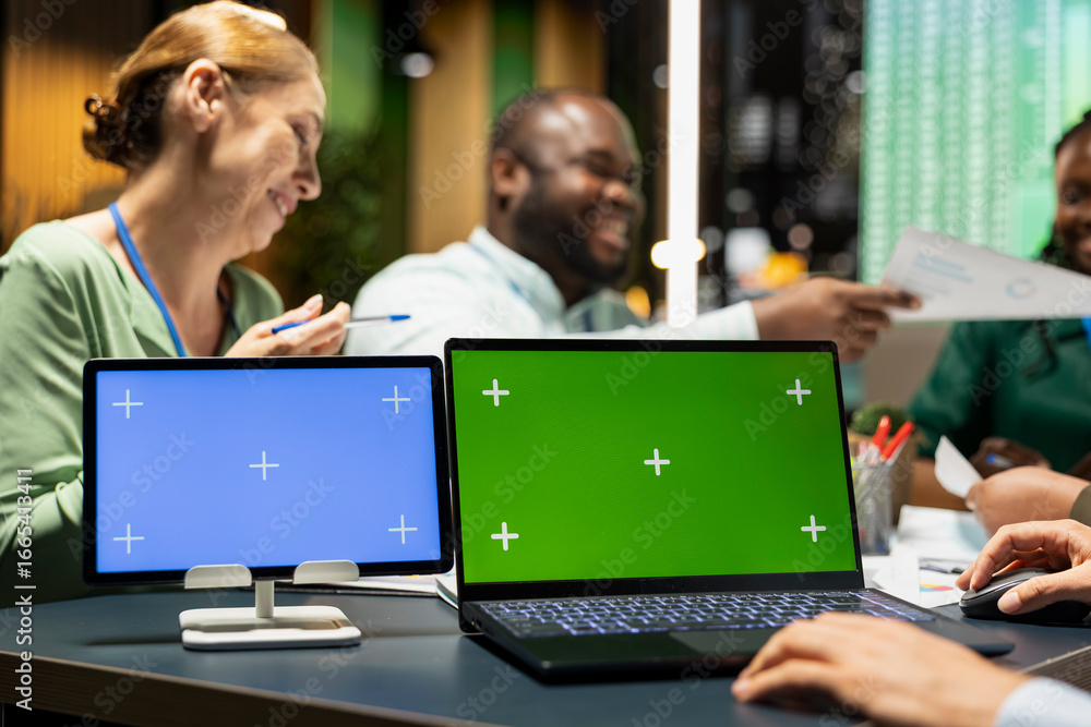 Poster coworkers attend strategy briefing with blue and green screen on devices, preparing performance proj