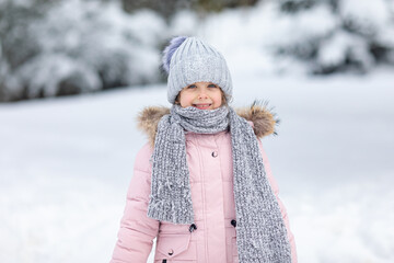 Winter portrait with copy space happy excited little girl in warm clothes playing in winter park...