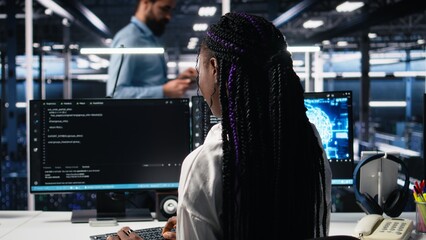 Technicians in data center review AI diagnostics, analyzing neural network performance to maintain operational reliability. IT workers optimize artificial intelligence systems configuration, camera A