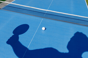 Shadow of table tennis player serving on blue court for training and education concepts