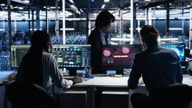 Server farm programmers seeing hacking warning, working to secure systems from cyberattack accessing confidential data. Team of data center coworkers fighting virus during security breach, camera A