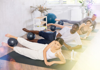 Group of active people doing soft ball pilates exercises during group pilates class in fitness...