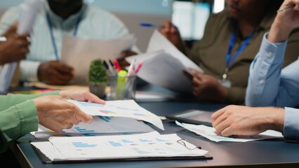 Close up of diverse specialists evaluating data numbers on archived files, exchanging reports and...