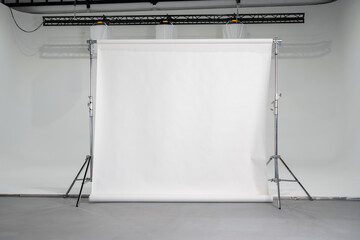 Empty professional photo studio setup with seamless white paper backdrop on stands, neutral background for portraits, product photography, or fashion shoots, symbolizing creativity, preparation