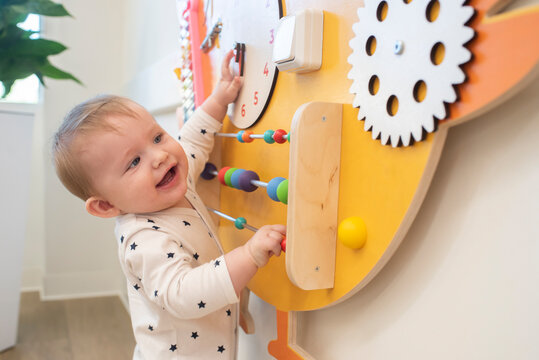 Baby boy playing with moving elements on busy board, development board.