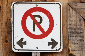 Weathered No Parking Sign on Wooden Wall with Directional Left and Right Arrows