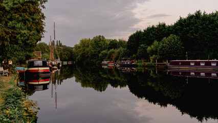 Obraz premium A serene scene of boats moored near a historic lock and dam architecture. Calm waters reflect the structures and vessels, capturing a peaceful moment of nautical life and industrial heritage.